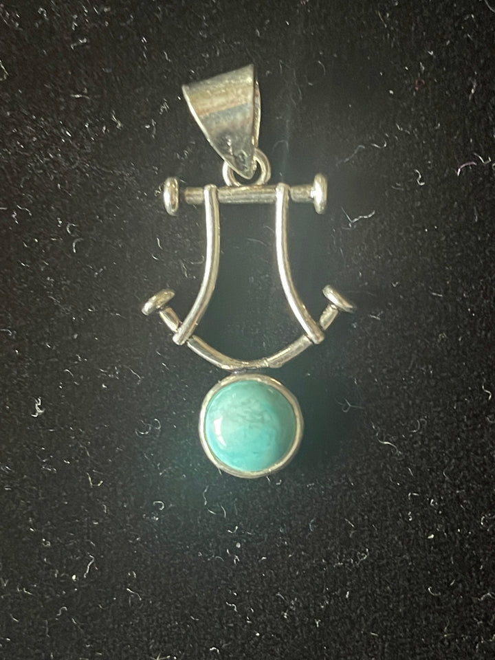 Turkoois 10mm, met een figuur van zilverdraad. Totaal                   17mmx20mm.3,6 gram € 15,-